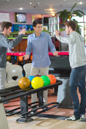 Young men bowling, poised to high five
