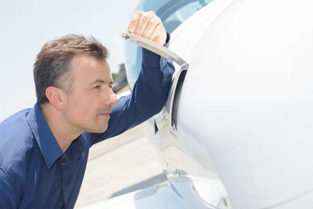 Man peering into compartment of airoplaneの写真素材