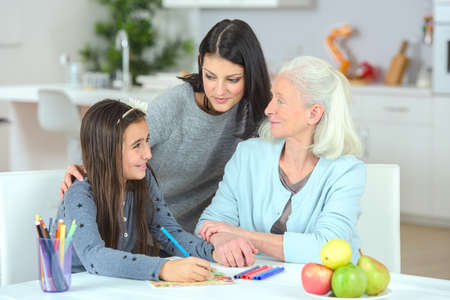 Little girl drawing with mother and grandmaの写真素材