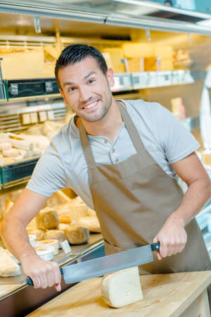 Local deli worker slicing some cheeseの写真素材
