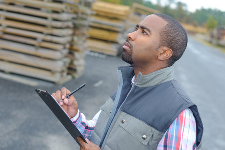 Man outdoors writing on clipboard