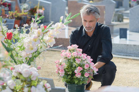 Man in black knelt at graveの写真素材