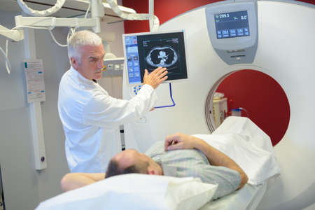 Man entering scanner, doctor stood besideの写真素材