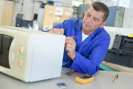 technician fixing a microwave oven