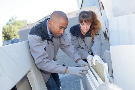 Male and female workers looking through building samplesの写真素材