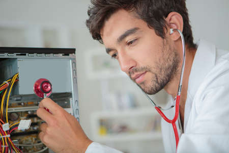 Computer repairman using stethoscopeの写真素材
