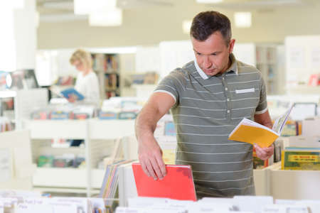 Man choosing book from trolley in libraryの写真素材