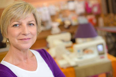 Portrait of mature woman, sewing machine in backgroundの写真素材