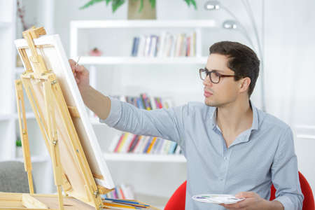 young painter drawing on a canvasの写真素材