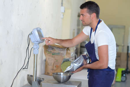 happy mid adult man weighing green peas on scaleの写真素材