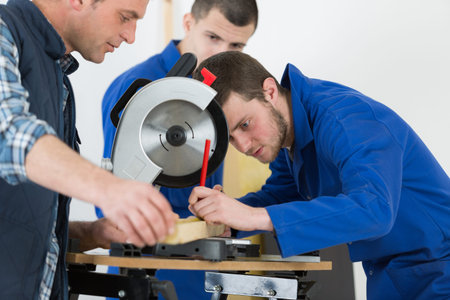 carpentry teacher showing sawing machine to students