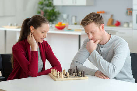 happy young couple playing chess in living roomの写真素材