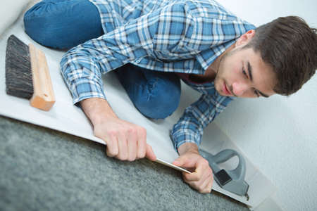 young male unrolling new floor at construction siteの写真素材