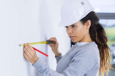 woman in builder uniform draing a plan on a wallの写真素材