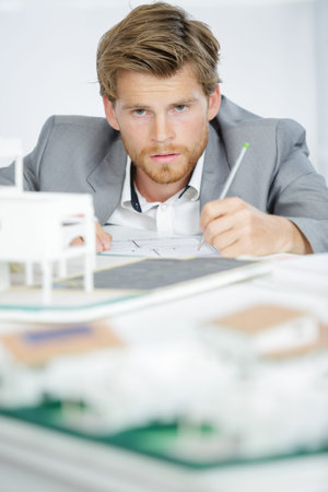 Architect making notes beside model building