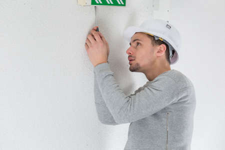 a male electrician fixing electric sign on the ceilingの写真素材