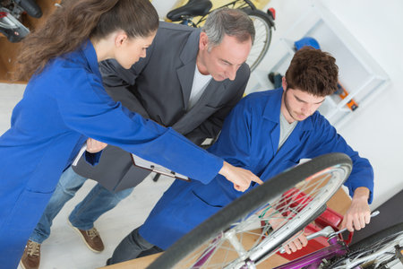 two apprentices show his manager how they repair a bicycle
