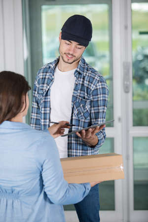 young woman receiving parcel from delivery manの写真素材