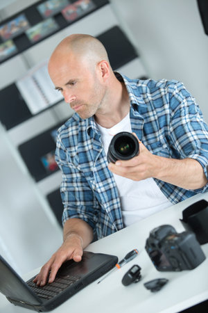 male middle-aged photographer sitting on the desk with laptop