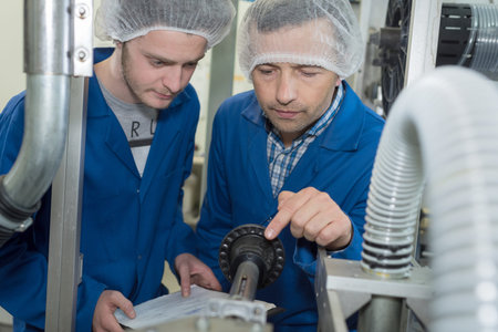 mechanics instructor teaching young man in apprenticeshipの写真素材