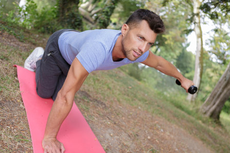 hansome man making exercises on mat outdoors