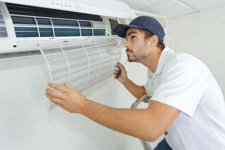 portrait of mid-adult male technician repairing air conditionerの写真素材