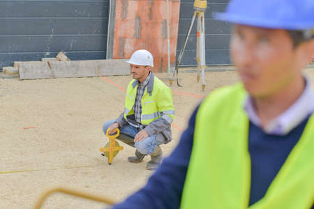 builders using measuring tools outdoors in a construction siteの写真素材