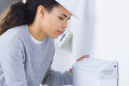 Female worker fitting appliance to wall
