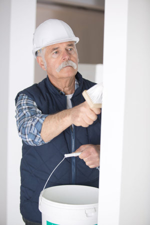 senior man painting a wall at construction siteの写真素材