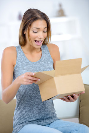 happy excited woman at home unboxing her gift