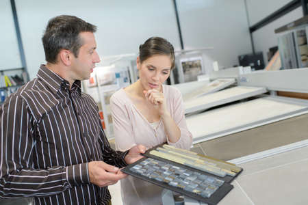 couple pointing at ceramic tile for bathroom floor in storeの写真素材
