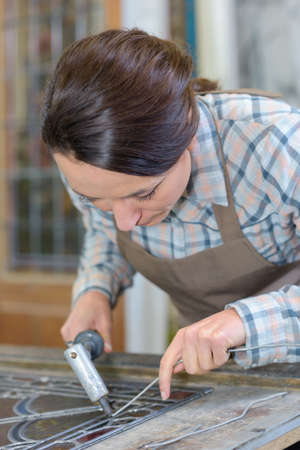 Woman applying lead to stained glassの写真素材