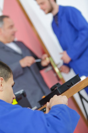 teacher with student in carpentry class fitting door lock