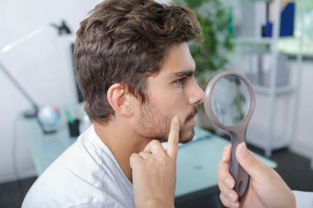 close-up of doctors hands checking mans molesの写真素材