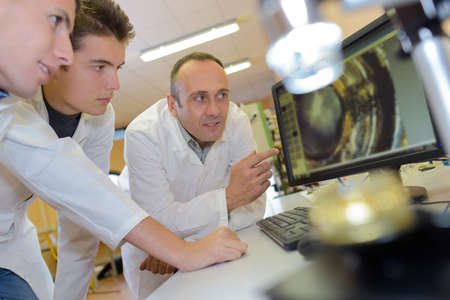 Students looking at magnified image on screenの写真素材