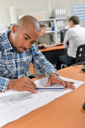 man measuring a blueprint