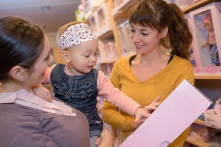 happy mom and daughter checking doll at the toy storeの写真素材
