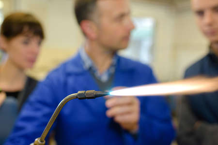 ironworks teacher showing students how to securely use gas welderの写真素材