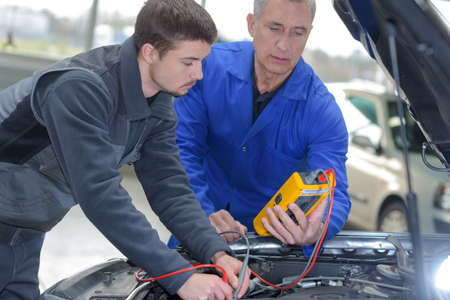 student with instructor repairing a car during apprenticeshipの写真素材