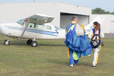 Man and woman walking with parachute at airfield