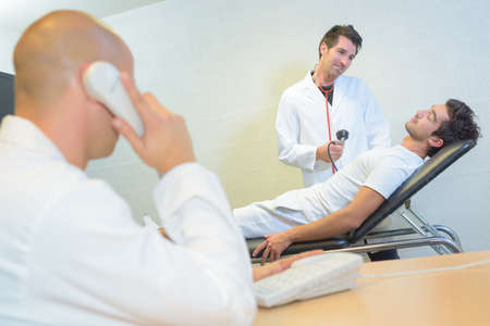 Doctor with patient, colleague on telephoneの写真素材
