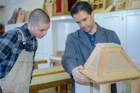 cabinetmaker teaching a young man his jobの写真素材
