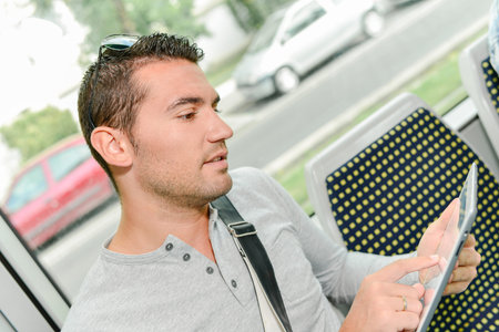 Using tablet computer during daily commuteの写真素材