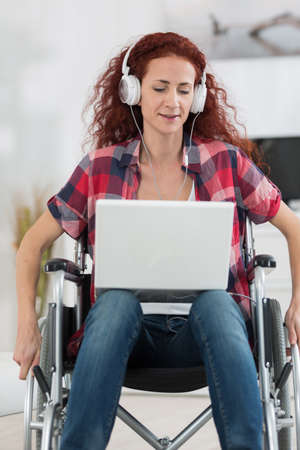 disabled woman with laptop and headphones relaxing at homeの写真素材