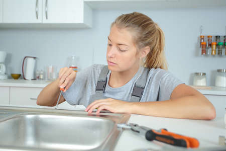 woman plumber unscrewing the sink screwsの写真素材