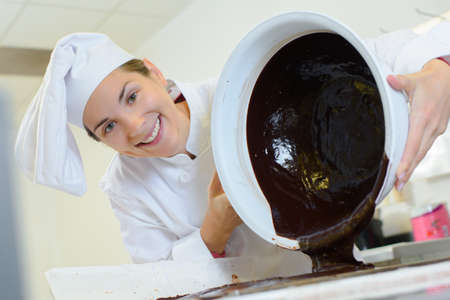 Chef pouring chocolate from bowlの写真素材