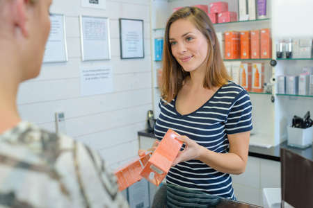 Shop assistant passing package to customerの写真素材