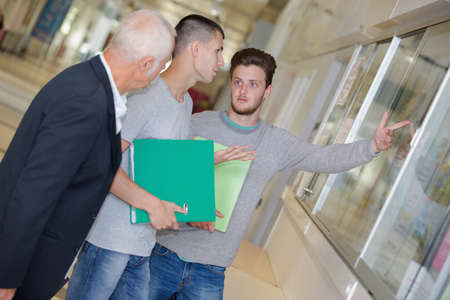 Men looking at poster behind frameの写真素材