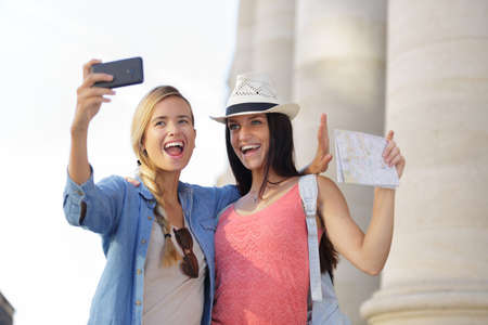 cheerful tourist female friends taking photos of themselvesの写真素材
