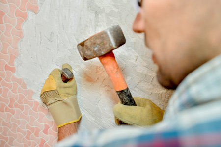 Man removing tiles from wall with hammer and chiselの写真素材
